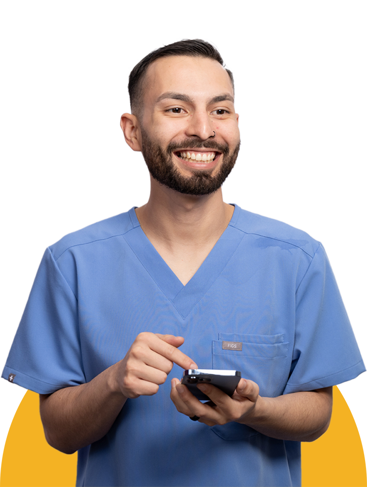 Male healthcare worker in scrubs smiling holding a phone