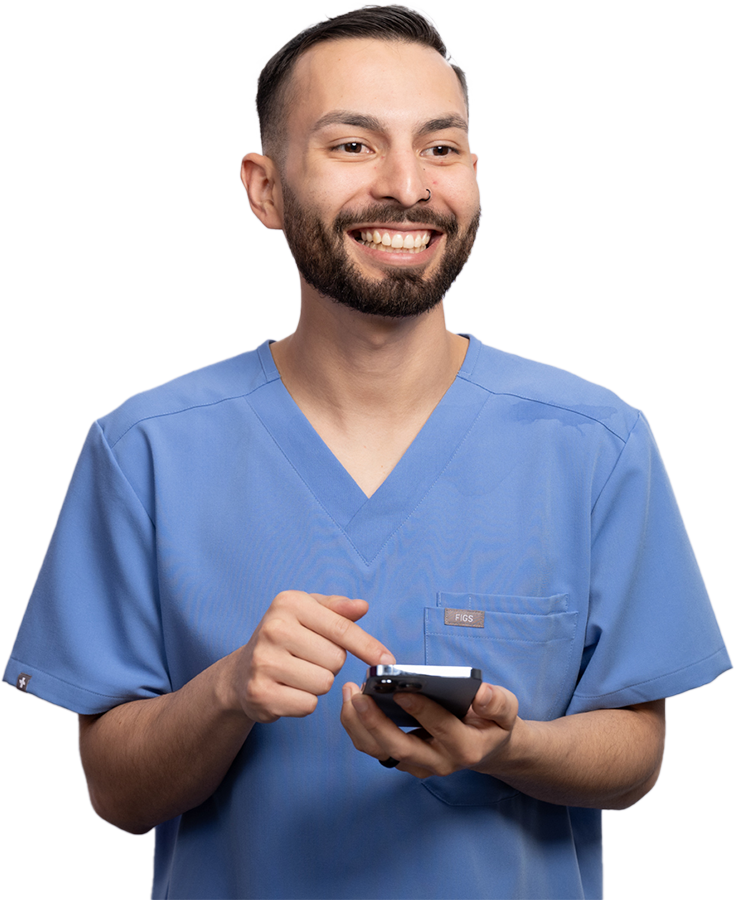 Male healthcare worker in scrubs smiling holding a phone