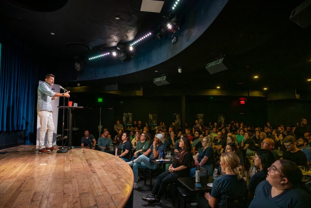 Photo of LiquidAgents CEO on stage talking to crowd of employees