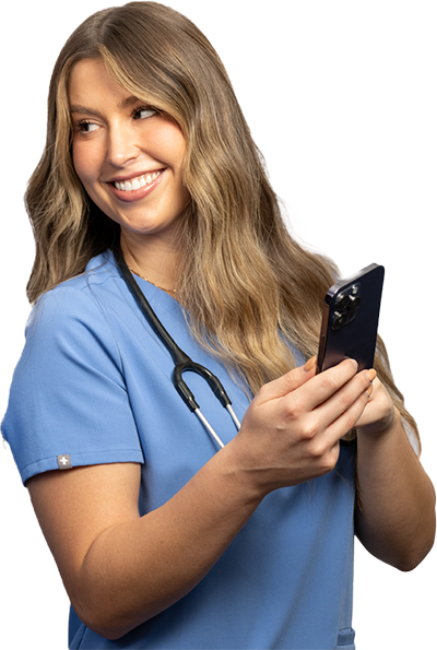A medical professional in a blue scrub top with a stethoscope around their neck is focused on a smartphone